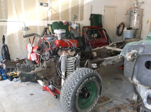 1979 Ford Bronco - The chassis and engine of a 1978 Ford Bronco are visible in a garage, alongside other vehicle parts.
