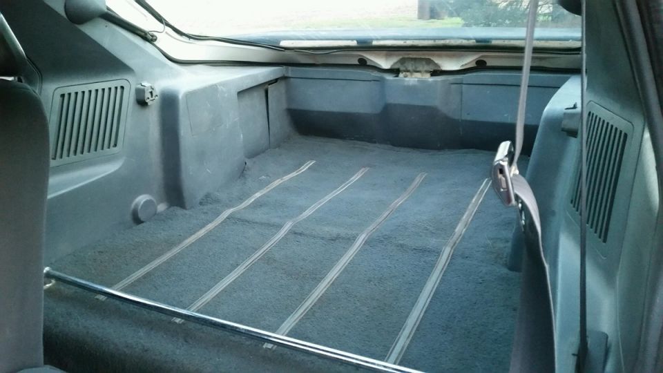 Carpeted rear cargo bed of an SUV with tailgate open