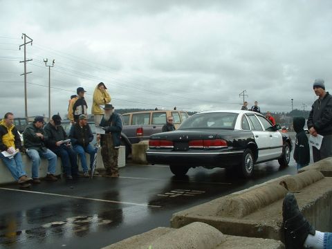 1999 Ford Crown Victoria - A black and white 1999 Ford Crown Victoria police car is viewed from the rear at an outdoor auction event.