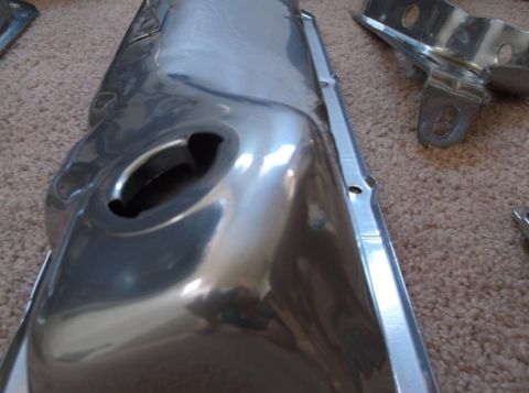 1979 Ford Bronco - A shiny chrome valve cover sits on a carpeted surface, with other metal components visible in the background.