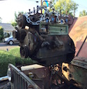 1946 Jeep Willys - An engine is hoisted out of an old Jeep, revealing the vehicle's chassis and surrounding area.