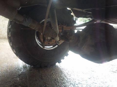 1978 Ford Bronco - The underside of a vehicle shows its rear axle, suspension components, and a tire.