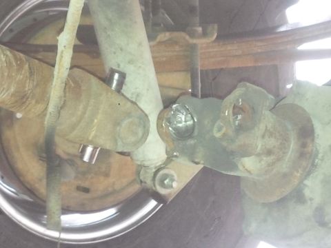 1978 Ford Bronco - Close-up view of rusty driveshaft and suspension components, with a chrome rim visible.