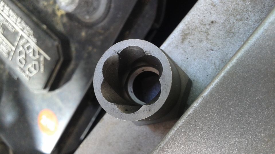Close-up of a star-shaped socket for a lug nut, near a car battery