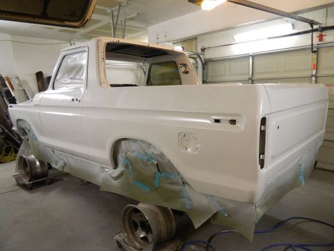 1979 Ford Bronco - A white Ford Bronco is being prepped for painting in a garage, with its body raised on stands.