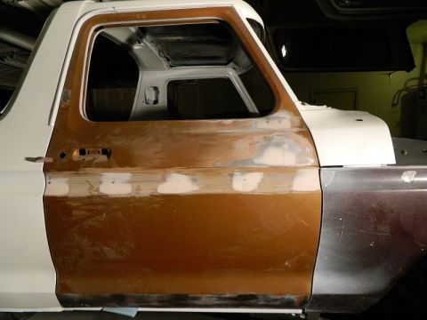 1979 Ford Bronco - This vehicle's side panel is being prepped for paint, showing areas with body filler and primer.