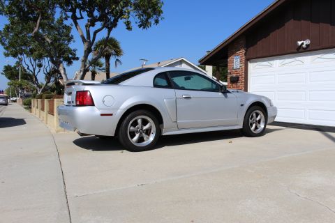 2002 Ford Mustang - This silver 2002 Ford Mustang coupe is seen from a 3/4 front angle, parked in a residential driveway.