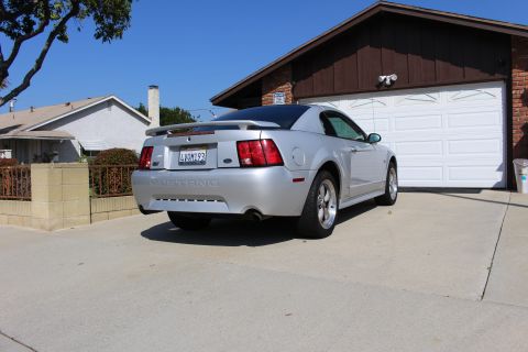2002 Ford Mustang - Rear view of a silver 2002 Ford Mustang parked in a driveway next to a garage.