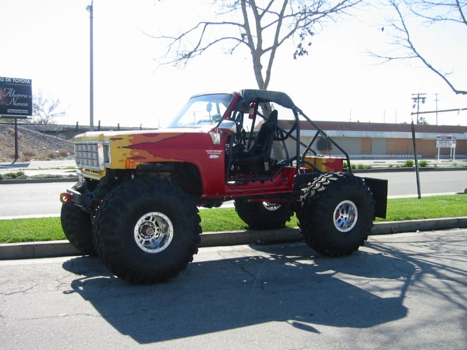 Red flamed lifted Chevy truck on huge tires with a roll cage