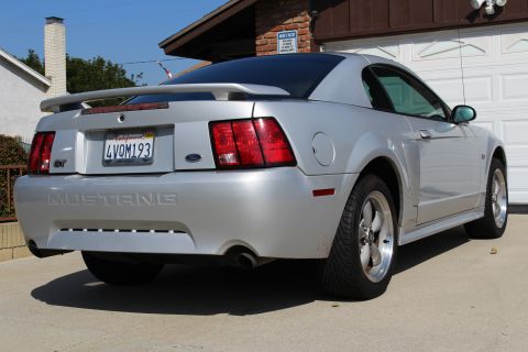 2002 Ford Mustang - Rear view of a silver Ford Mustang with a spoiler and custom plate.