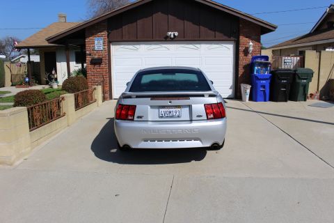 2002 Ford Mustang - Rear view of a silver 2002 Ford Mustang parked in front of a garage.