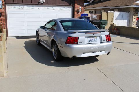 2002 Ford Mustang - This silver 2002 Ford Mustang GT is parked in front of a garage door.