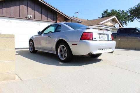 2002 Ford Mustang - The rear of a silver 2002 Ford Mustang GT is shown, its distinctive taillights, spoiler, and GT badging.
