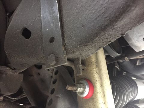 1995 Ford Bronco - Underbody view shows a red polyurethane suspension bushing and a black steering rack boot, with visible frame components.