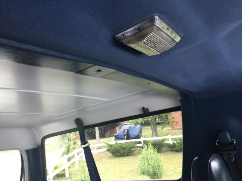 1995 Ford Bronco - View from inside a vehicle, looking out a window at another vehicle covered by a blue tarp.