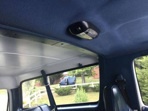 1995 Ford Bronco - View from inside a 1995 Ford Bronco, looking out the rear window at a covered vehicle in the yard.