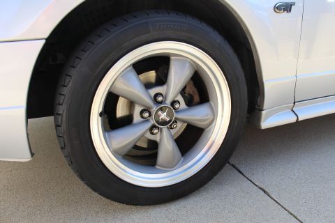 2002 Ford Mustang - Close-up of a silver Ford Mustang GT's wheel and side body panel, showing the GT emblem.