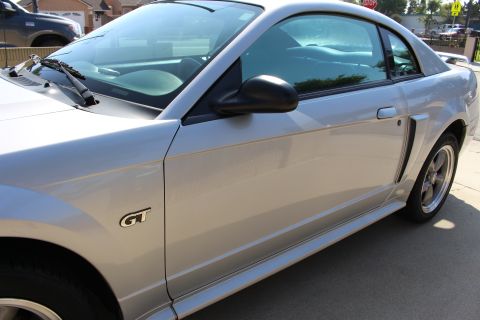 2002 Ford Mustang - Side profile of a silver 2002 Ford Mustang GT coupe, showing the door, fender, and wheel.