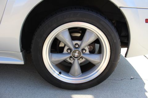 2002 Ford Mustang - A silver 2002 Ford Mustang wheel with a running horse emblem is shown up close.