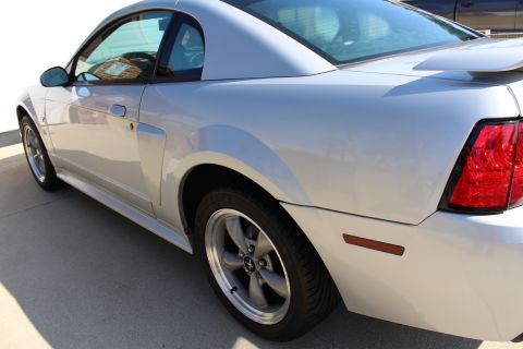 2002 Ford Mustang - This silver 2002 Ford Mustang coupe is viewed from the rear three-quarter angle, highlighting its body style and spoiler.