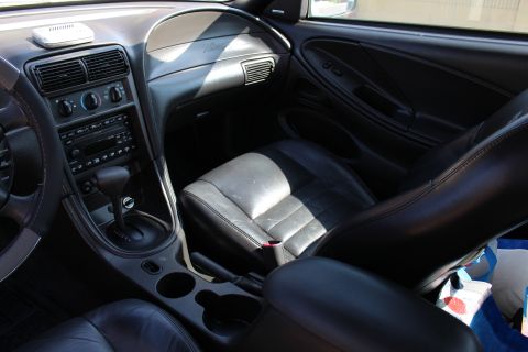 2002 Ford Mustang - The interior of a 2002 Ford Mustang is visible, black leather seats and the dashboard.