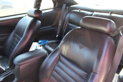 2002 Ford Mustang - The interior of a 2002 Ford Mustang features black leather seats with a horse emblem embossed on the passenger seat.