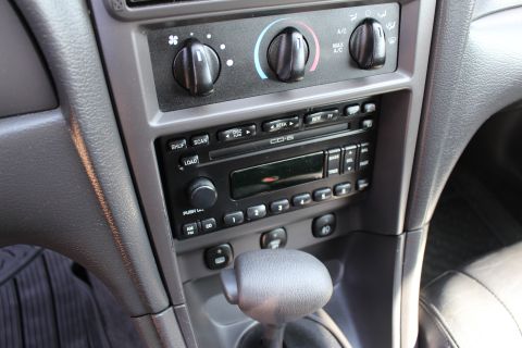 2002 Ford Mustang - Close-up of the center console in a 2002 Ford Mustang, showing the radio and climate control knobs.