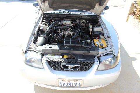2002 Ford Mustang - Front view of a silver 2002 Ford Mustang with its hood open, revealing the engine compartment and front grille.