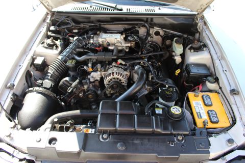 2002 Ford Mustang - Engine bay of a 2002 Ford Mustang showing the V8 engine, battery, and air intake system.