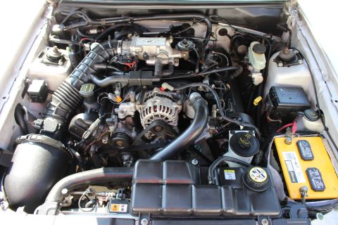 2002 Ford Mustang - The engine compartment of a 2002 Ford Mustang is visible, with the V8 engine prominently displayed.