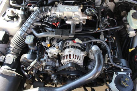 2002 Ford Mustang - The engine bay of a 2002 Ford Mustang is visible, the V8 engine and a running pony emblem.