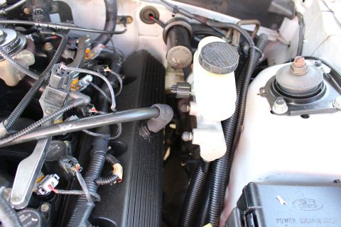 2002 Ford Mustang - Close-up view of the engine bay, showing the brake fluid reservoir, various hoses, and wiring.