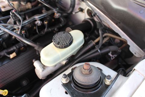2002 Ford Mustang - The brake fluid reservoir and surrounding engine parts are visible in this engine bay shot.