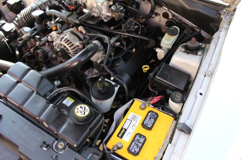 2002 Ford Mustang - The engine bay of a 2002 Ford Mustang shows a yellow battery, coolant reservoir, and alternator.