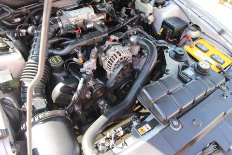 2002 Ford Mustang - The engine bay of a 2002 Ford Mustang is visible, with the V8 engine and associated parts clearly displayed.