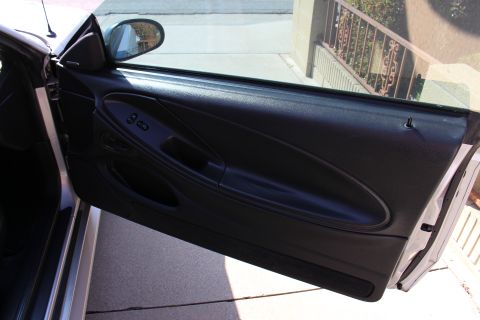 2002 Ford Mustang - The interior door panel of a 2002 Ford Mustang shows black upholstery and window controls.