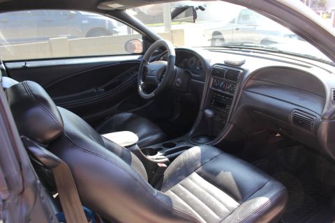 2002 Ford Mustang - The interior of a 2002 Ford Mustang features black leather seats and a detailed dashboard.