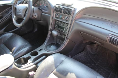 2002 Ford Mustang - The interior of a 2002 Ford Mustang features leather seats, a standard dashboard layout, and a center console with an automatic shifter.