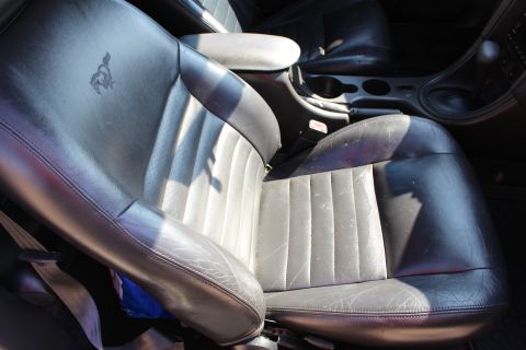 2002 Ford Mustang - Interior view of black leather seats with a running horse emblem and center console.
