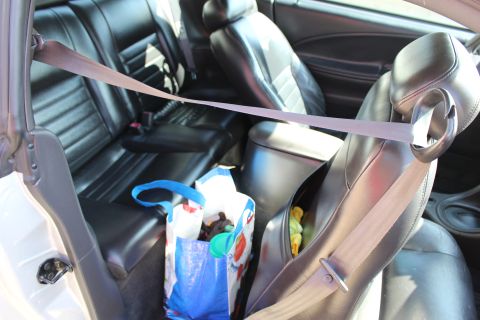 2002 Ford Mustang - The interior of a 2002 Ford Mustang features black leather seats and seatbelts, with a shopping bag in the back seat.