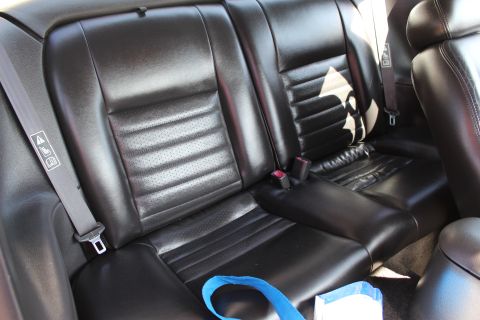 2002 Ford Mustang - Rear seats of a car, showing black leather upholstery and seat belts.