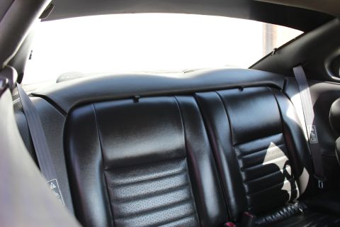 2002 Ford Mustang - Interior shot of a car's rear seats, showing black leather upholstery and seatbelts.