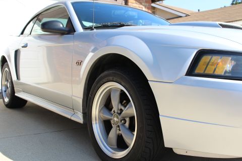 2002 Ford Mustang - A silver 2002 Ford Mustang GT is viewed from the front three-quarter angle, highlighting its distinctive body style and GT badging.