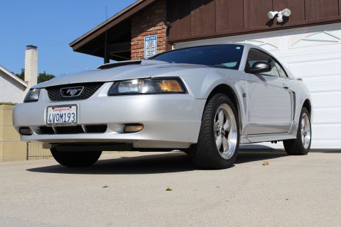 2002 Ford Mustang - Silver 2002 Ford Mustang with California plates parked in front of a garage.