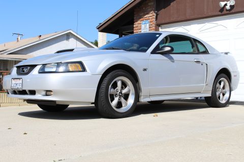 2002 Ford Mustang - A silver 2002 Ford Mustang coupe is parked in front of a garage and house.