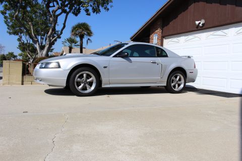 2002 Ford Mustang - Side view of a silver 2002 Ford Mustang parked on a concrete driveway.