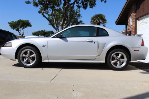 2002 Ford Mustang - Side profile of a silver 2002 Ford Mustang GT coupe parked on a driveway.