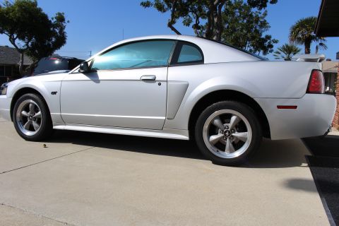 2002 Ford Mustang - Silver 2002 Ford Mustang GT with tinted windows and a rear spoiler is shown from the side.