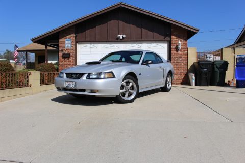 2002 Ford Mustang - Silver 2002 Ford Mustang coupe parked in front of a brick house with a garage.