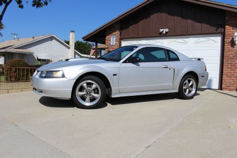 2002 Ford Mustang - Silver 2002 Ford Mustang GT parked in front of a garage on a sunny day.
